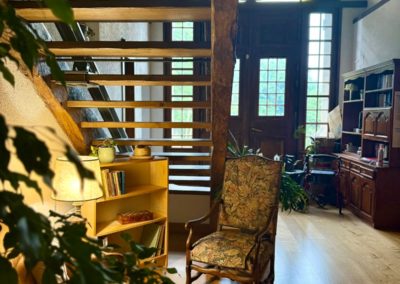 Le hall d'entrée de la maison, son escalier en bois et le vitrail au-dessus de la porte