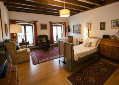 Chambre Érables : la chambre sous les poutres, avec ses deux fenêtres cintrées et le coin salon